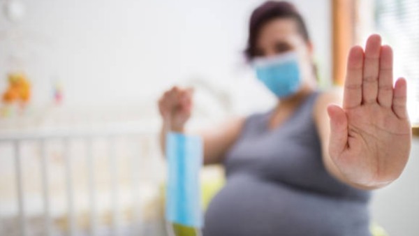 Ilustrasi ibu hamil mengenakan masker pelindung, mencerminkan kewaspadaan terhadap risiko COVID-19 pada janin.