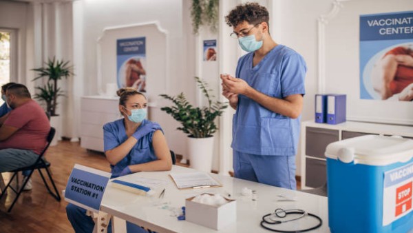 Tenaga medis tengah mempersiapkan vaksin COVID dengan latar ruang klinik