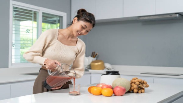 Ilustrasi seorang perempuan menuangkan smoothie buah segar ke dalam gelas.
