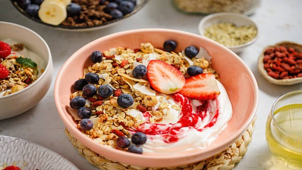 Semangkuk oatmeal dan yogurt dengan topping buah segar sebagai pilihan sarapan sehat.
