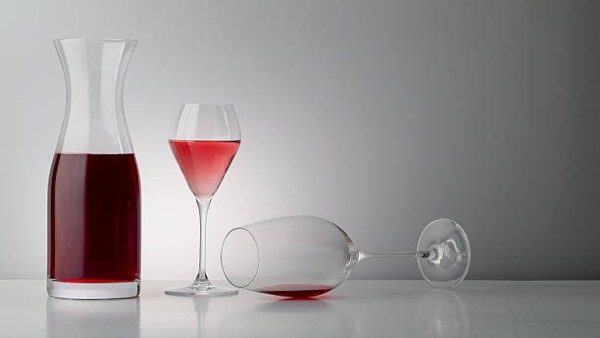 Segelas anggur merah di atas meja putih, simbol pilihan hidup sehat bebas alkohol.