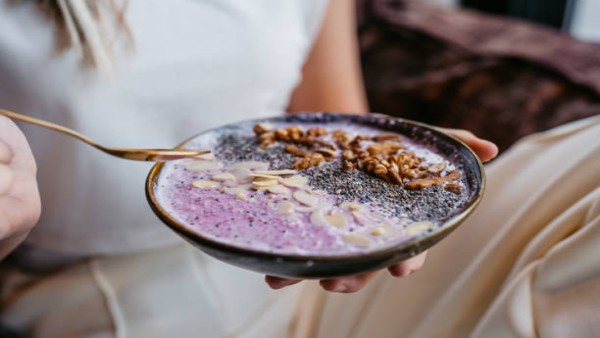 Wanita menikmati smoothie bowl sehat sebagai contoh menu “hyperfixation meal” yang sederhana dan membantu menjaga berat badan.