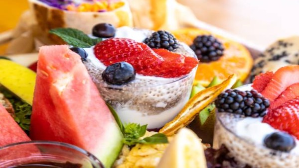 Ilustrasi aneka camilan manis sehat seperti chia pudding, yogurt beku, dan buah segar.