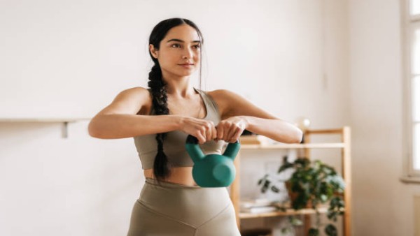 Seorang wanita melakukan latihan kettlebell untuk menjaga kekuatan otot dan kebugaran tubuh di usia lanjut.