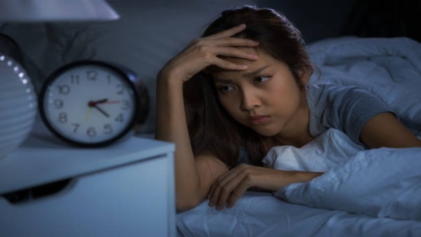 Ilustrasi seorang wanita mengalami kesulitan tidur di malam hari dan mencoba menenangkan diri sebelum kembali beristirahat.