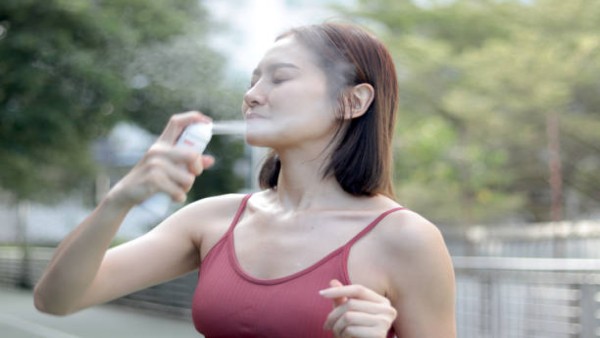 Seorang warga menyejukkan tubuh dengan semprotan air saat cuaca panas ekstrem untuk mengurangi risiko gangguan kesehatan akibat suhu tinggi.